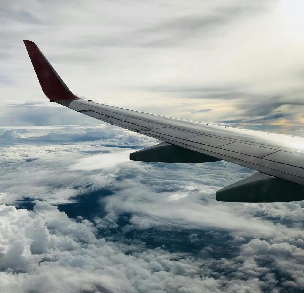 A stunning aerial view of fluffy clouds and an airplane wing during daylight flying.